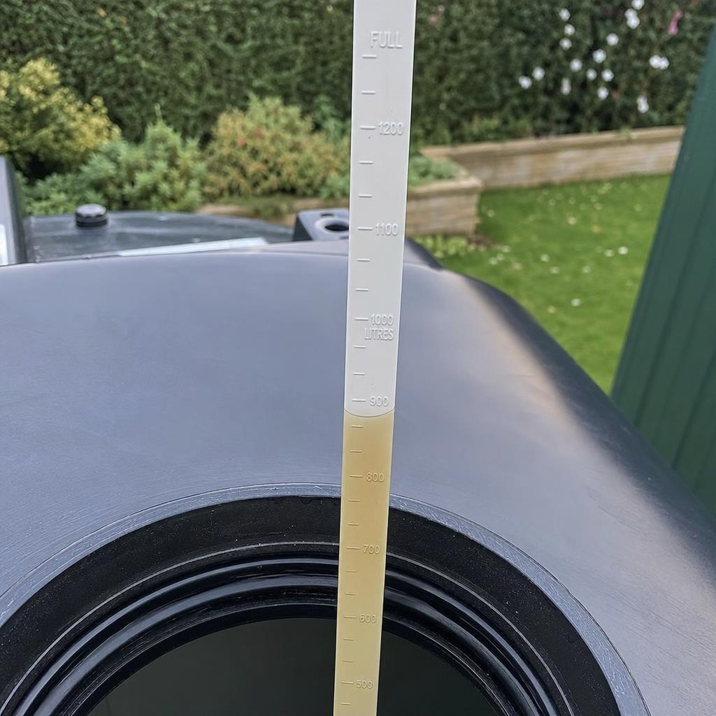 Measuring oil depth with a dipstick inside a plastic storage tank
